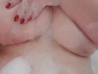 4XL Frau massiert sich ihre schaumigen Brüste im Bad